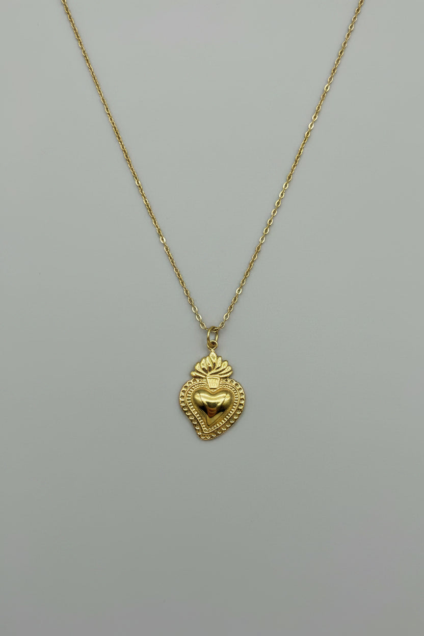 Collana con pendente Sacro Cuore in acciaio color oro antico con dettagli a rilievo, bordo decorato e fiamma, su catena sottile a maglia rolo dorata
