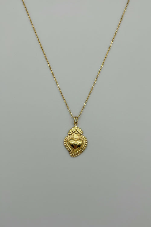Collana con pendente Sacro Cuore in acciaio color oro antico con dettagli a rilievo, bordo decorato e fiamma, su catena sottile a maglia rolo dorata