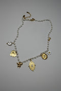 Collana a filo di perle bianche con 5 charm dorati: cuore sacro, farfalla, medaglione barocco, sole con cristallo e margherita smaltata