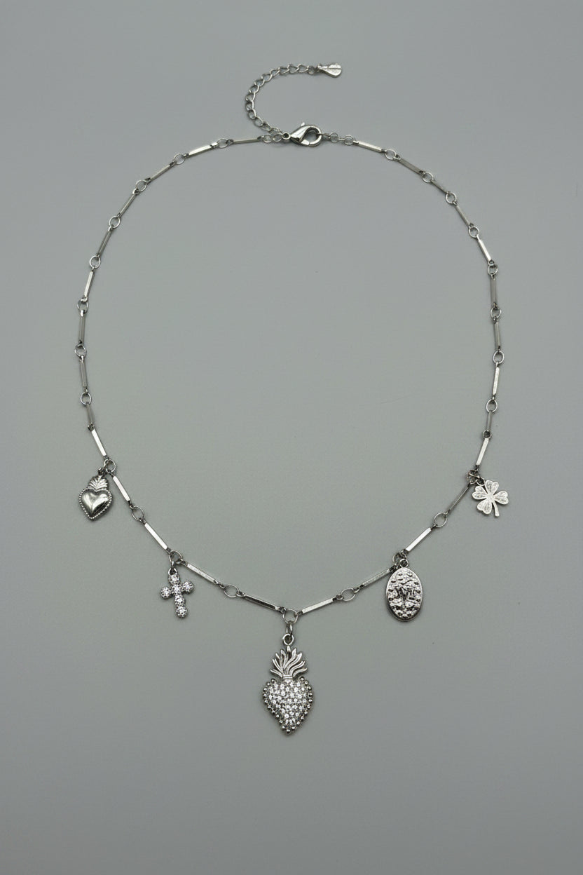 Collana a catena lingottini in acciaio argentato con 5 charm: sacro cuore con brillantini, croce, medaglione ovale, cuore liscio e quadrifoglio