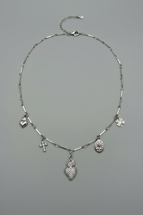 Collana a catena lingottini in acciaio argentato con 5 charm: sacro cuore con brillantini, croce, medaglione ovale, cuore liscio e quadrifoglio
