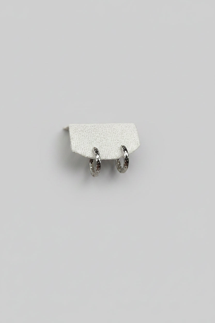 Orbis Caelatus — orecchini a cerchio huggie martellato 16mm in acciaio argento, coppia